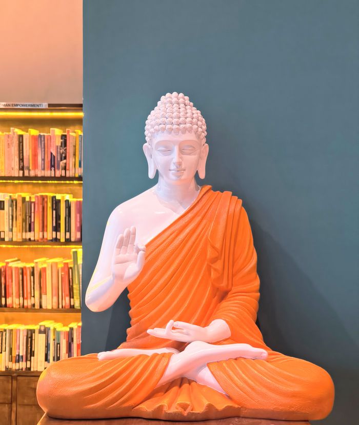 Mastering the First Impression: Your intriguing post title goes here Meditative Buddha statue with hand raised, set against bookshelves in India.